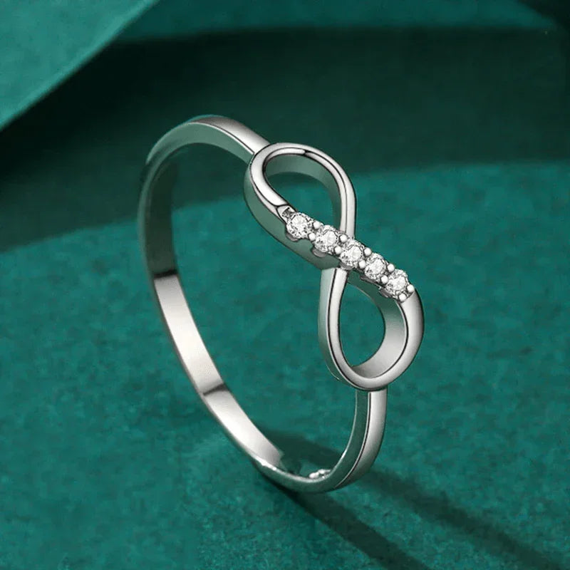 Sterling silver infinity ring with cubic zirconia stones on green background