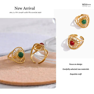 Gold rings with green and red stones on a white background