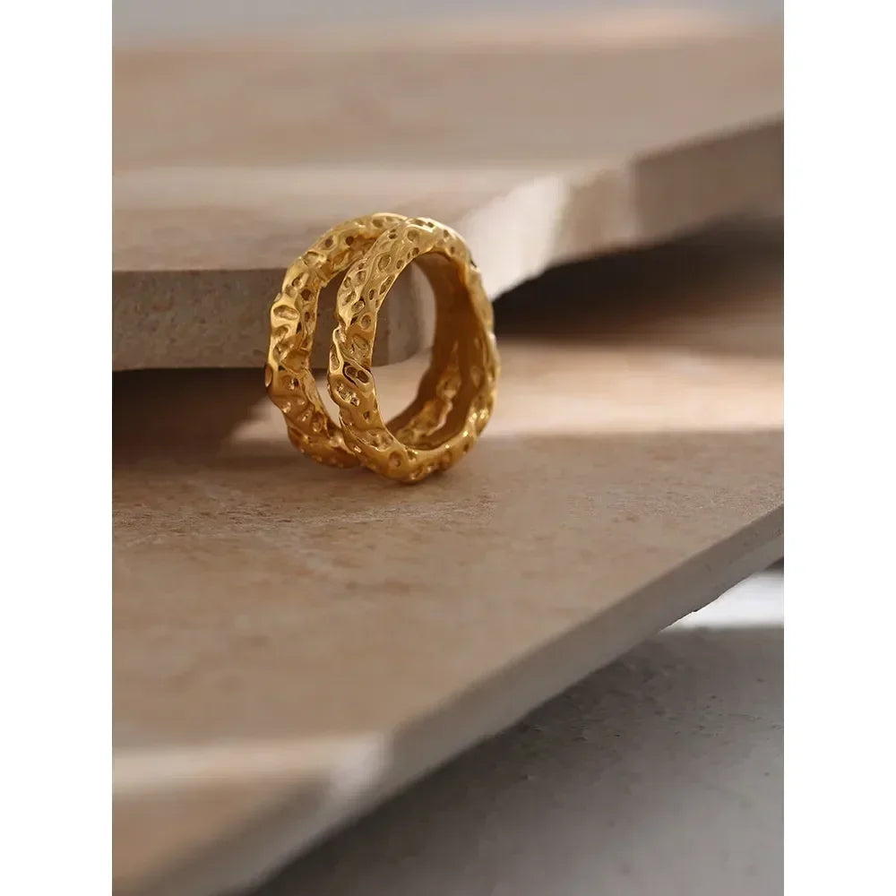 Textured 18K gold-plated rings stacked on neutral stone surface, handcrafted jewelry