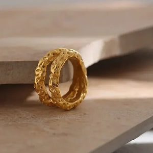 Textured 18K gold-plated rings stacked on neutral stone surface, handcrafted jewelry