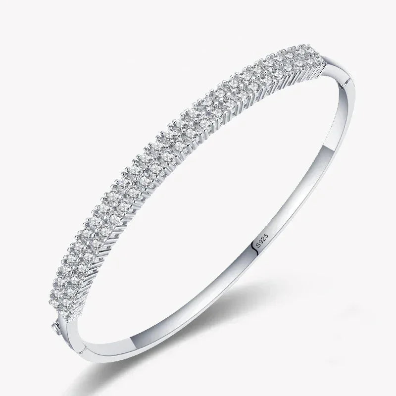 Sterling silver bangle with three rows of sparkling cubic zirconia stones on white background