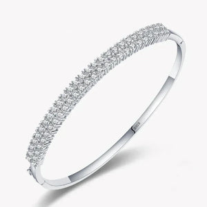 Sterling silver bangle with three rows of sparkling cubic zirconia stones on white background