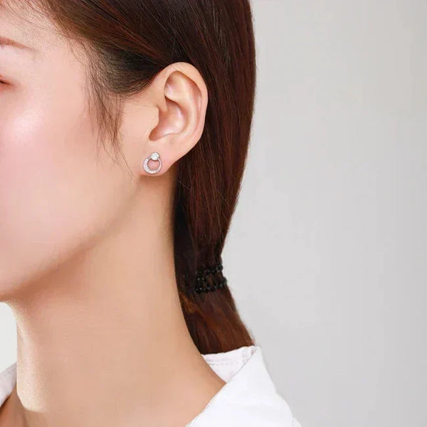 Close-up of a person wearing a silver earring on a plain background