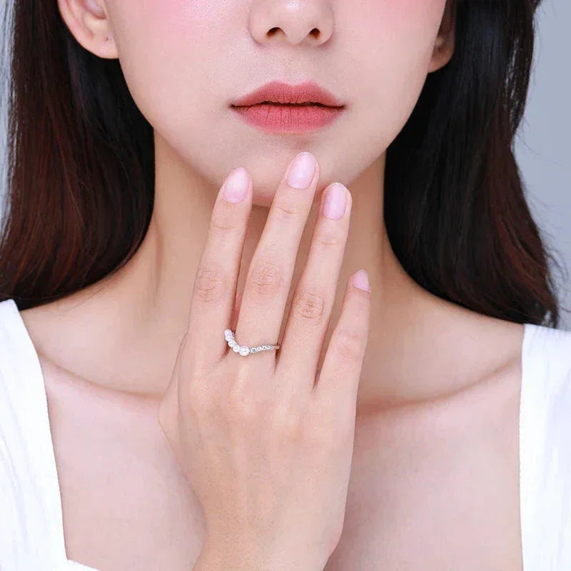 Woman wearing a delicate 925 silver ring with pearls, elegant jewelry on hand