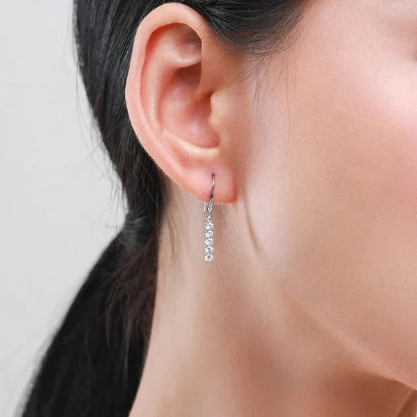 Close-up of an ear wearing a silver earring with a blurred background