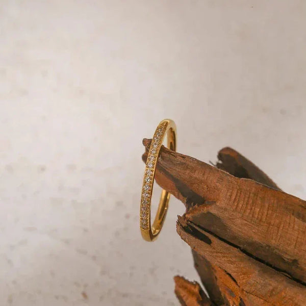 Gold-plated silver ring with small clear stones displayed on wood, elegant jewelry for women
