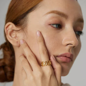 Woman wearing a gold-plated statement ring, hand posed near face, elegant style
