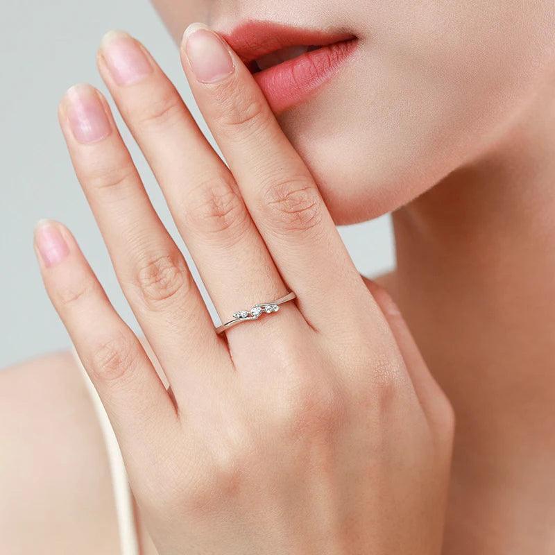 Woman wearing minimalist 925 silver ring with three small sparkling stones on finger