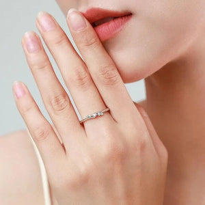 Woman wearing minimalist 925 silver ring with three small sparkling stones on finger