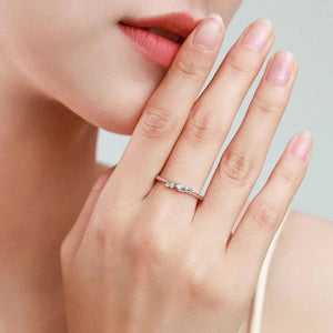 Woman wearing a delicate silver ring with three small clear gemstones on her finger