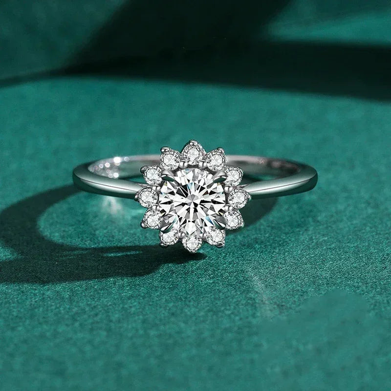 Silver ring with flower-shaped cluster of clear gemstones on green background