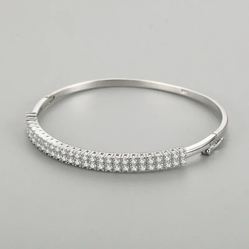 Sterling silver bangle with three rows of sparkling cubic zirconia stones on a grey background