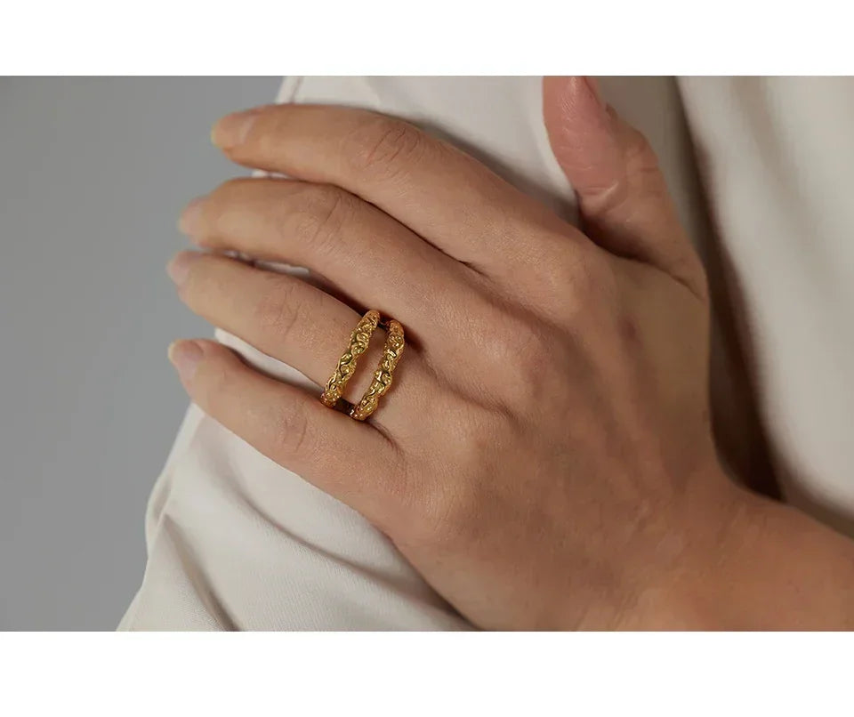 Hand wearing two textured 18K gold-plated rings on middle finger, elegant jewelry