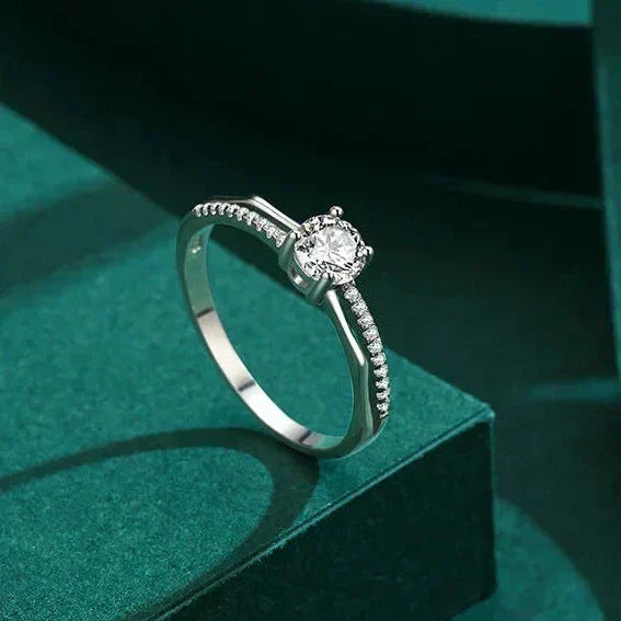 Silver ring with a diamond on a green surface, labeled 'Real Shotshow'.
