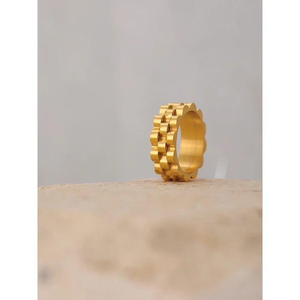 Gold-plated geometric band ring with scalloped edges on a neutral background
