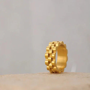 Gold-plated geometric band ring with scalloped edges on a neutral background