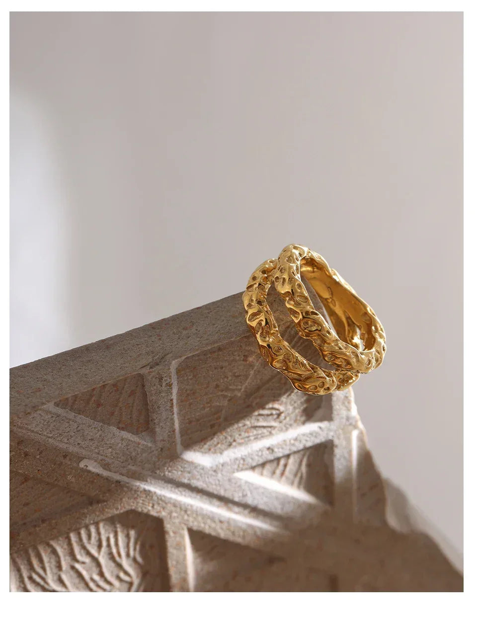 Textured 18K gold-plated silver ring with organic design on a stone surface