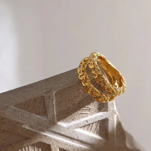 Textured 18K gold-plated silver ring with organic design on a stone surface