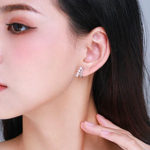 Woman wearing elegant silver and pearl stud earrings, close-up on ear and jewelry.