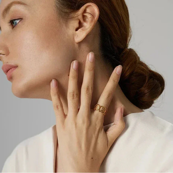 Woman wearing a gold-plated statement ring, hand posed near face, elegant style