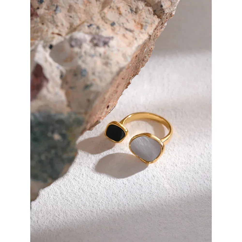 Gold-plated adjustable ring with black and white stones on textured surface