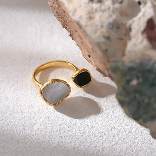Gold-plated adjustable ring with black and white stones on textured surface