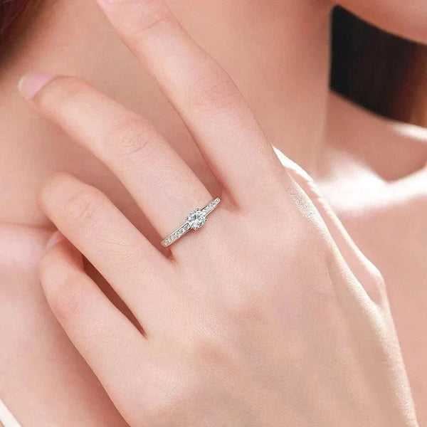 Woman wearing a sterling silver solitaire ring with round-cut center stone and pavé band