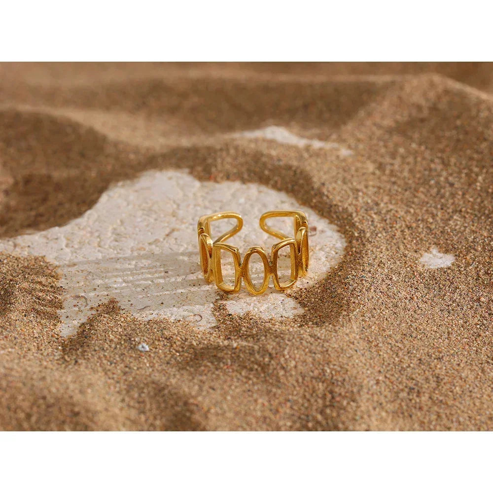 18K gold-plated open ring with geometric design displayed on sandy surface