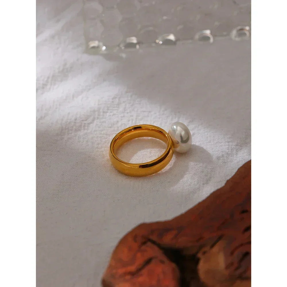 18K gold-plated ring with single pearl accent on white fabric background