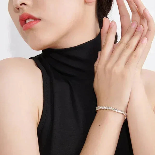 Woman wearing a black sleeveless top and bracelet on a white background