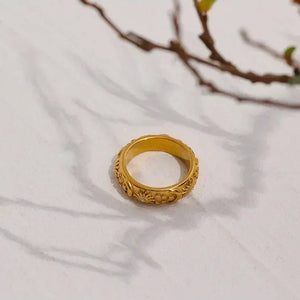 18K gold-plated floral engraved ring on light surface with tree branch shadow