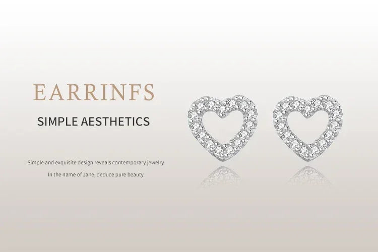 Heart-shaped silver stud earrings with sparkling stones on a light background.