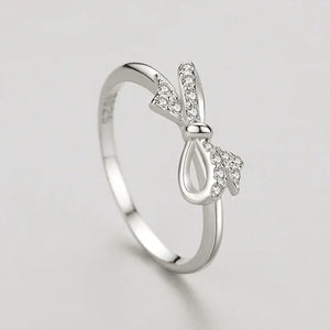 Silver ring with bow design on a light gray background
