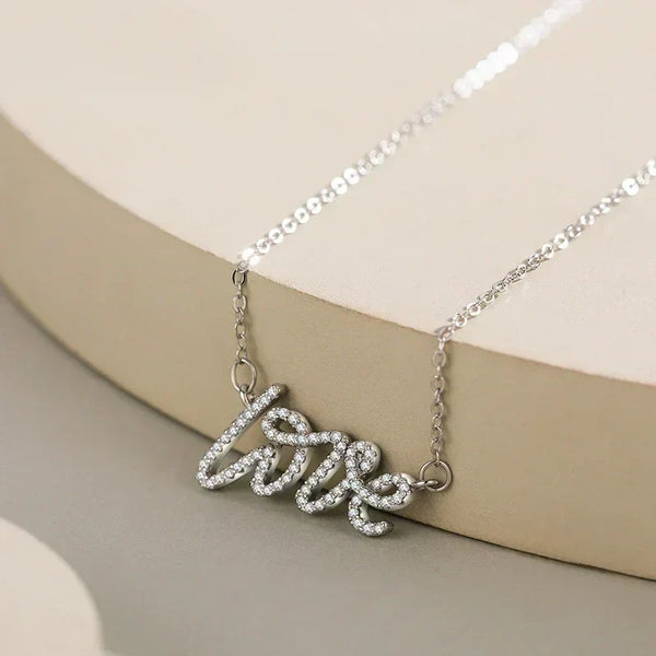 Silver 'love' necklace on a beige background