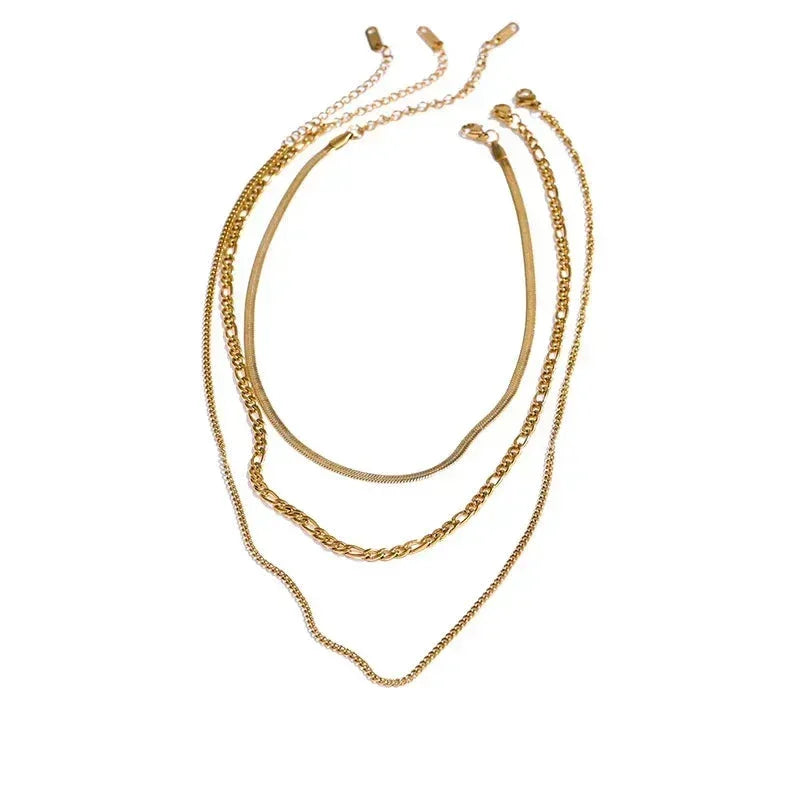 Four layered gold-plated chain necklaces with different link styles on white background