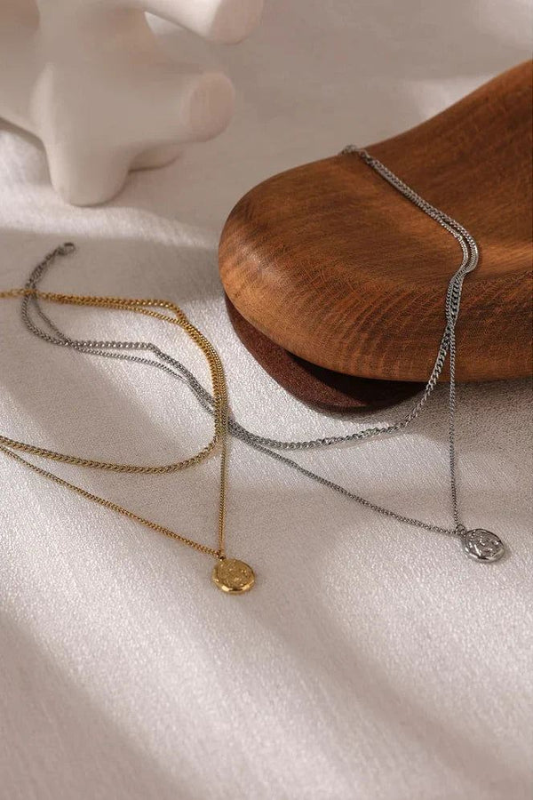 Three necklaces on a white surface with a wooden block