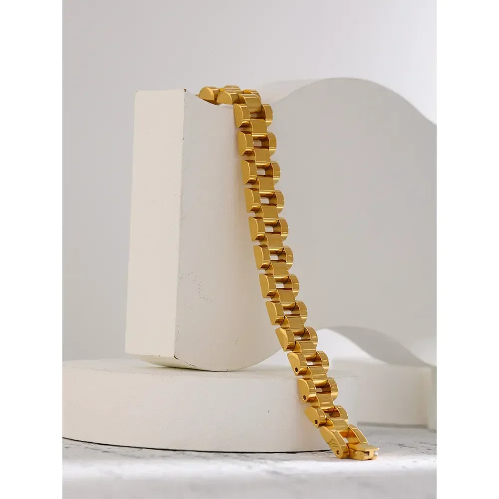 Chunky gold-plated chain link bracelet displayed on white geometric props