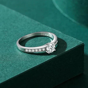 Silver ring with a heart-shaped diamond on a green surface