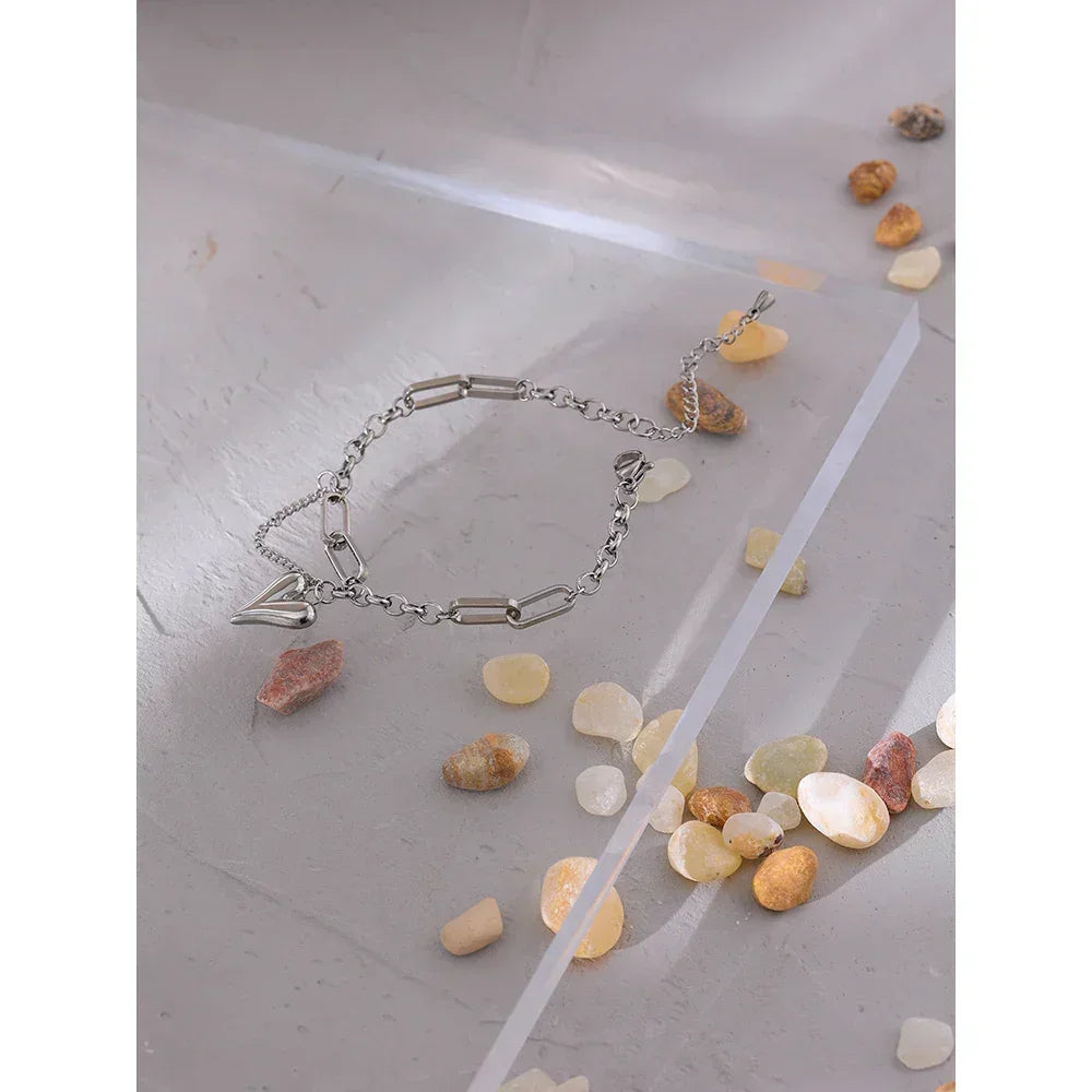 925 silver chain bracelet with geometric links and charm, displayed on stone surface with pebbles