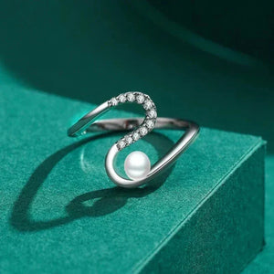 Silver ring with a pearl on a green surface