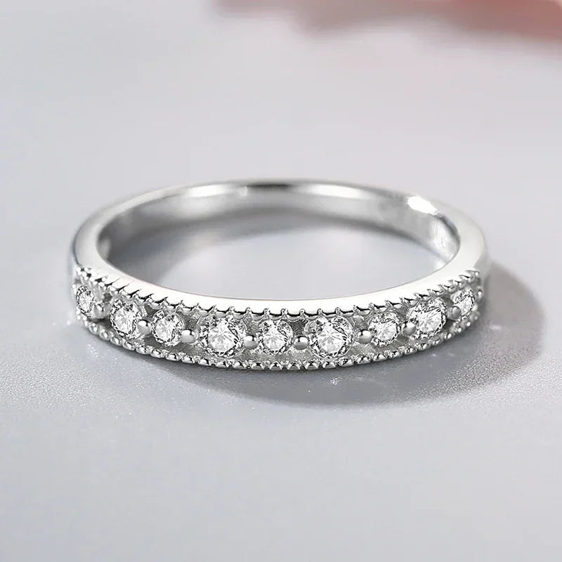 Sterling silver ring with row of round cut clear stones on a reflective surface