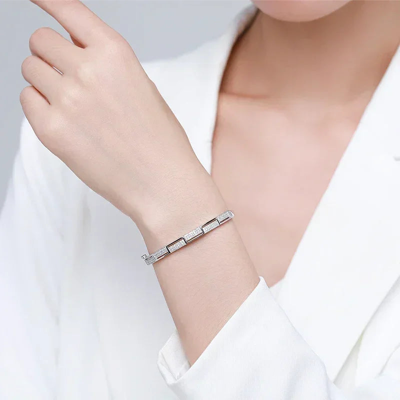 Woman wearing a geometric 925 silver bracelet with pavé stones on wrist, elegant jewelry style