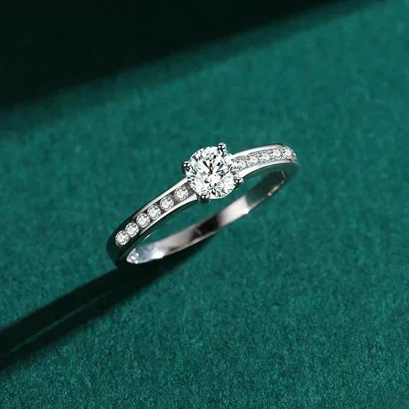Silver ring with small diamonds on a green surface with white flowers.