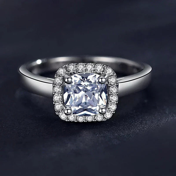 Silver ring with a large diamond and smaller diamonds around on a dark background