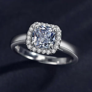 Silver ring with a large diamond and smaller diamonds around on a dark background