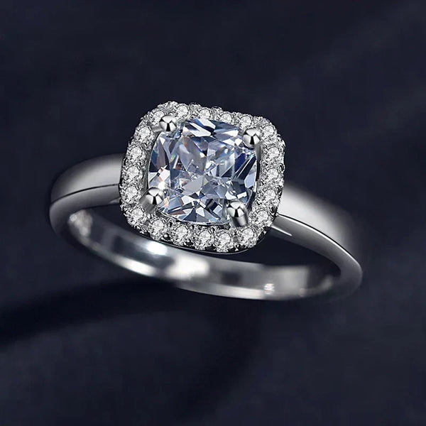 Silver ring with a large diamond and smaller diamonds around on a dark background