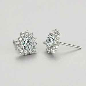 Pair of silver earrings with clear gemstones on a light gray background