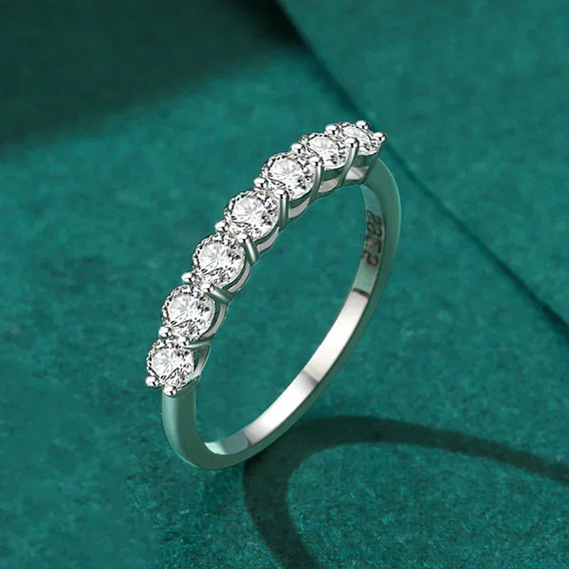 925 silver ring with row of round-cut clear gemstones on teal background