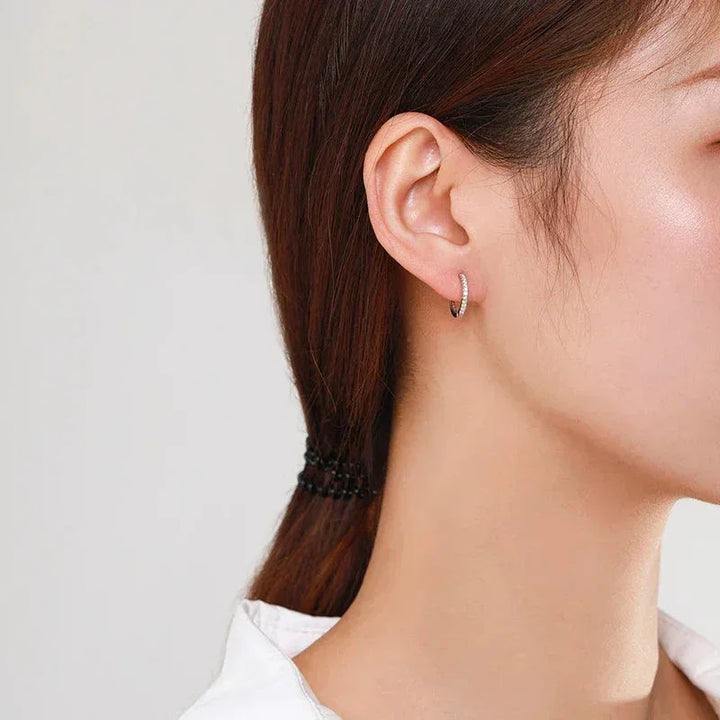 Woman wearing a small, elegant 925 silver hoop earring with pavé stones