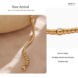 18K gold-plated beaded bracelet with single clear gem on geometric display